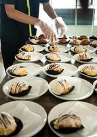 hotell anställda är framställning mellanmål kakor på plattor innan de möte. många rader av plattor med buffé snacks. foto