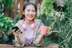 ung asiatisk kvinna med smartphone i trädgården foto