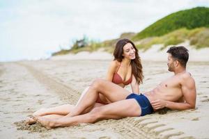 ungt par sitter tillsammans på sanden på stranden foto