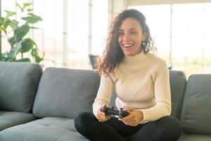 laitinsk kvinna som spelar tv-spel med händer som håller joysticken foto