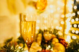 två champagne glasögon fylld med champagne är placerad på en tabell med en frukt arrangemang. de glasögon är omgiven förbi lampor, skapande en festlig atmosfär. foto