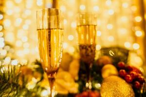 två champagne glasögon fylld med champagne är placerad på en tabell med en frukt arrangemang. de glasögon är omgiven förbi lampor, skapande en festlig atmosfär. foto