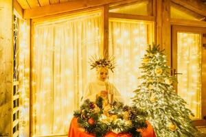 Lycklig leende kvinna i en vit klänning innehav en champagne glas i främre av en jul träd. foto