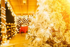 snötäckt jul träd med ljus vit lampor belägen utomhus nära en byggnad, en välkomnande festlig ögonblick. foto