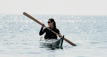 kvinna hav kajak. Lycklig leende kvinna i kajak på hav, paddling med trä- åra. lugna hav vatten och horisont i bakgrund. aktiva livsstil på hav. sommar semester. foto