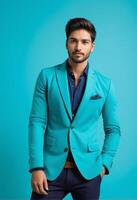 ai genererad självsäker ung söder asiatisk man klädd i en eleganta turkos blazer Framställ mot en blå bakgrund, idealisk för mode och företags- händelse teman foto