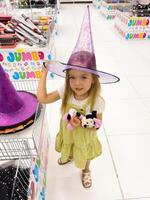 podgorica, monte - 14 augusti 2023. liten flicka påfrestande på spetsig lila häxa hatt i affär foto