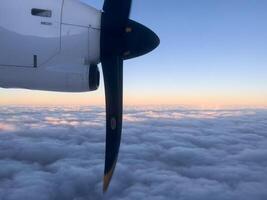 roterande propeller av ett flygplan flygande ovan de moln i de solnedgång himmel foto