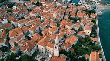 vit klocka torn av de kyrka av st. ivan bland de röd tak av de gammal hus av budva. montenegro. Drönare foto