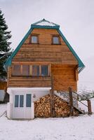 trä- tvåvånings hus med en vedtrave under de trappa i en snöig by foto