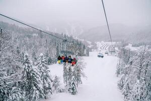 åka skidor hiss med skidåkare rider upp en snötäckt berg ovan de skog av de kolasin 1600 tillflykt. monte foto