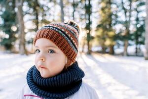 liten omtänksam flicka står i en snöig skog och utseende bort foto