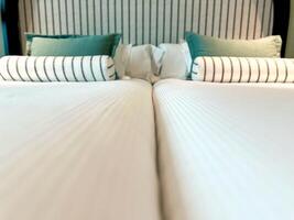säng hembiträde med rena vit säng ark och grön kuddar i skönhet rum. tvilling säng närbild. foto