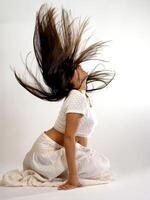 ung kvinna knästående i vit med flygande hår foto