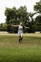 ung caucasian kvinna löpning på grön gräs vapen utsträckt foto