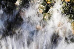 vatten ström besprutning över mossa täckt stenar foto