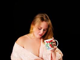 ung caucasian kvinna bär morgonrock innehav kaffe kopp foto