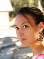 ung asiatisk kvinna utomhus- porträtt fjäril örhängen foto