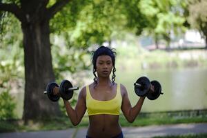 ung svart kvinna i parkera med vikter foto