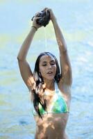 ung kvinna simma kostym vatten häller på huvud foto
