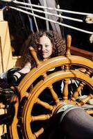 blandad arv kvinna stående på styrning hjul lång fartyg foto