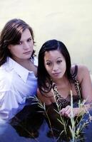 två ung kvinnor Sammanträde i flod utomhus foto