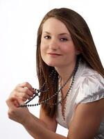 ung kvinna i vit blus innehav pärla halsband foto