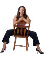 ung svart kvinna staddling stol i byxor utrusta foto