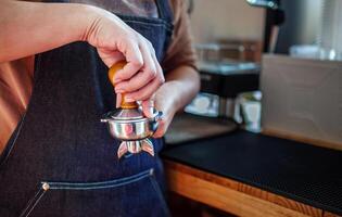 närbild av hand Barista Kafé framställning kaffe med manuell trycker på jord kaffe använder sig av manipulera på de kaffe affär foto