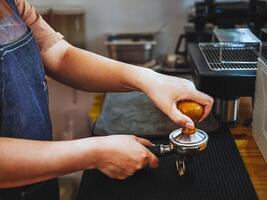 närbild av hand Barista Kafé framställning kaffe med manuell trycker på jord kaffe använder sig av manipulera på de kaffe affär foto