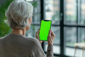 ai genererad ett äldre kvinna är innehav en cell telefon med en grön skärm foto
