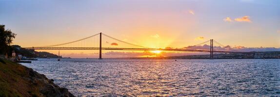 panorama av 25 de abril bro över tagus flod på solnedgång. Lissabon, portugal foto