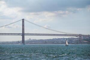 se av 25 de abril bro över tagus flod med en Yacht båt. Lissabon, portugal foto