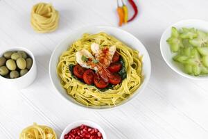 spaghetti med spenat, tomater och räka. skaldjur. Hem produktion. foto