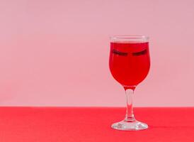 kreativ layout med glas av röd vin och falsk ögonfransar på rosa och röd bakgrund. mode skönhet romantisk sammansättning. retro estetisk fest eller firande aning. Lycklig liv begrepp. foto