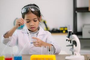 asiatisk barn flicka inlärning vetenskap kemi med testa rör framställning experimentera på skola laboratorium. utbildning, vetenskap, kemi, och barns begrepp. tidigt utveckling av barn. foto