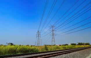 två torn av högspänning elektricitet poler den där korsa över de dubbelspår järnväg spår foto
