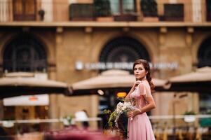 en ung skön brud står på de Centrum av de gammal stad av florens i Italien. brud i en skön rosa klänning med en bukett i tuscany.italy foto