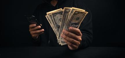 smartphone och pengar i svart hoodie man hand foto