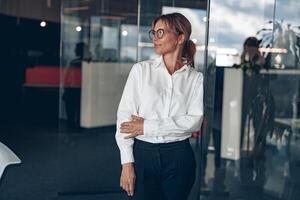 fokuserade företag kvinna bär glasögon utseende bort under de arbetssätt dag på modern kontor foto