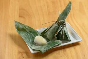 japansk mat sasa mochi ris kaka wraps med banan blad i en maträtt isolerat på trä- bakgrund topp se foto