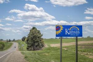 kansas välkomnar du, Välkommen vid vägkanten tecken med en populär latin fras ad astra per aspera, genom svårigheter till de stjärnor, körning och resa begrepp foto