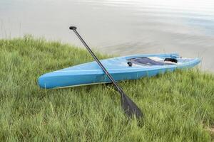 touring stå upp paddelbräda med en paddla på en gräs- sjö Strand foto