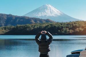 kvinna turist njut av med fuji berg på sjö saiko, Lycklig resande sightseeing montera fuji och väg resa fuji fem sjöar. landmärke för turister attraktion. japan resa, destination och semester foto