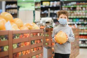 pojke bär skyddade mask i Lagra. handla tid under coronavirus utbrott.pojke i en medicinsk mask. karantän och skydd virus, influensa, epidemi covid19. coronavirus karantän foto