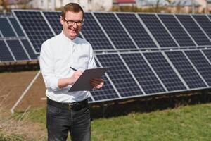 sol- paneler och blå sky.man stående nära sol- paneler. sol- panel producerar grön, miljömässigt vänlig energi från de Sol. foto