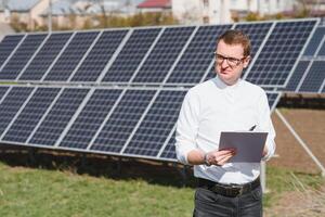 sol- paneler och blå sky.man stående nära sol- paneler. sol- panel producerar grön, miljömässigt vänlig energi från de Sol. foto