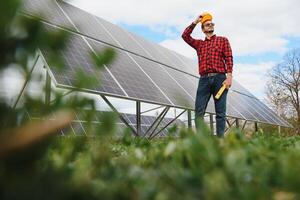 sol- paneler och blå sky.man stående nära sol- paneler. sol- panel producerar grön, miljömässigt vänlig energi från de Sol. foto