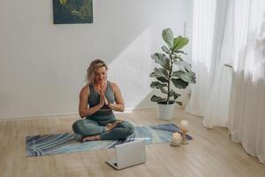 en 50-åring kvinna håller på med uppkopplad yoga på Hem foto