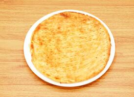 sheermal taftan, naan eller kulcha, roti eras i en maträtt isolerat på trä- tabell sida se av indian, pakistansk mat foto